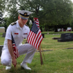 An ROTC cadet from Oregon State University places flags on the graves of military veterans at Crystal Lake Cemetery